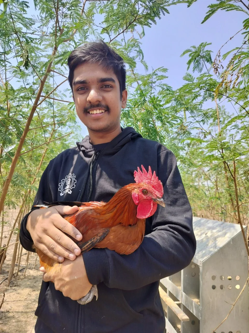 A member of the Siddhi Farm family holding one of the farm's desi roosters